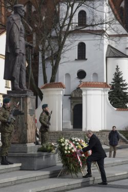Mężczyzna składa wieniec przed pomnikiem Józefa Piłsudskiego.