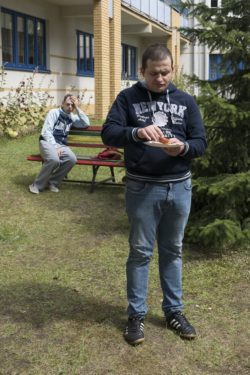 Stojący mężczyzna trzyma talerzyk z kiełbaską.