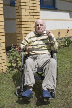 Mężczyzna na wózku inwalidzkim trzyma talerzyk.
