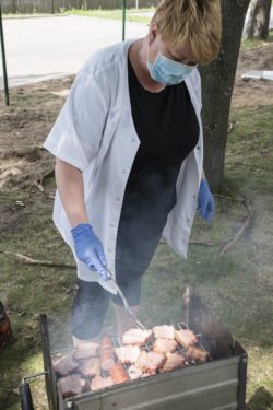 Kobieta stojąca przy grillu z kiełbaskami.