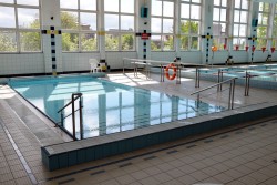 Widok przedstawiający nieckę basenu rekreacyjnego z wejściem po schodach i barierkami