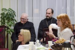 Duchowni: katolicki i prawosławny oraz dwie kobiety przy stole.