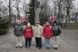 Zdjęcie grupowe. Pięć osób przed pomnikiem Armi Krajowej.