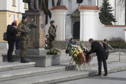 Mężczyzna składa wieniec przed pomnikiem Józefa Piłsudskiego.