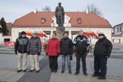 Zdjęcie grupowe. Sześć osób stoi przed pomnikiem Józefa Piłsudskiego.