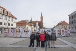 Zdjęcie grupowe. Sześć osób stoi na placu przed dużym napisem Białystok.