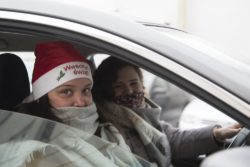 Dwie kobiety w samochodzie. Jedna z nich ma na głowie czerwoną czapkę z napisem: wesołych świąt.