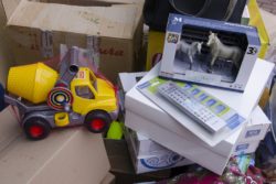 Różnokolorowe pudełka i zabawki. Żółty samochód - betoniarka, dwa koniki, pilt do telewizora.