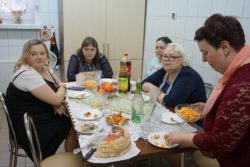 Pięć kobiet siedzi wokół zastowionego słodkościami stołu.