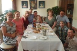 Zdjęcie grópowe. Pięć kobiet, trzej chłopcy i jeden mężczyzna siedzących wokół stołu. Na stole tależyki i słodycze.