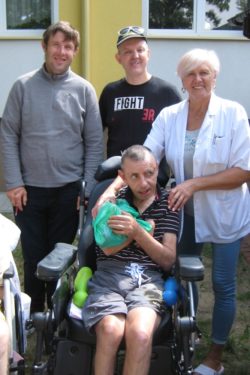 Zdjęcie grópowe. Trzech mężczyzn, jeden z nich na wózku inwalidzkim i kobieta.