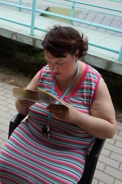 Siedząca na krześle kobieta czyta książkę.