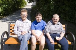 Trzech mężczyzn siedzących na ławce.