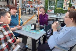 Cztery kobiety trzymające przekąski w ręku siedzące przy restauracyjnym stoliku.