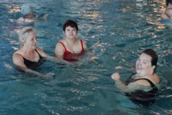 Trzy kobiety w strojach kąpielowych w basenie.