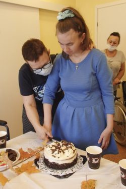 Dwie kobiety wspólnie kroją tort.