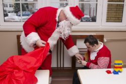 Mikołaj dający słodycze chłopcu siedzącemu przy stoliku.