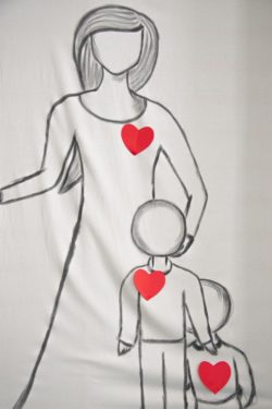 Trzy różnej wielkości postacie namalowane na płótnie z przyklejonymi czerwonymi sercami.