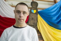 Chłopiec stojący na tle dekoracji z flagami Polski i Ukrainy.