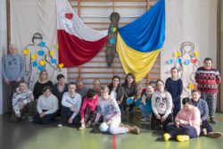 Zdjęcie grupowe. Kobiety i mężczyźni na tle dekoracji w barwach Polski i Ukrainy.