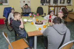 Dzieci siedzące wokół zastawionego słodyczami stołu.