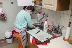 Kobieta zmywająca brudne naczynia.