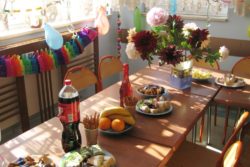 Stół na którym stoją słodycze, napoje i wazon z kwiatami.