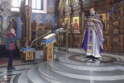 Wnętrze cerkwi i Batiuszka stojący przed ikonostasem.