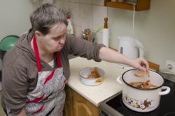 Kobieta wrzucająca do stojącego na kuchence garnka łupiny po cebuli.