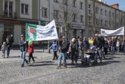 Grupa osób maszerująca ulicą, niosąca baner z napisem Dom Pomocy Społecznej ul Baranowicka 203