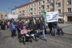 Grupa osób maszerująca ulicą, niosąca baner z napisem Dom Pomocy Społecznej ul Baranowicka 203