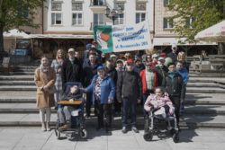 Grupa osób stojąca na placu przed kamienicą z baner z napisem Dom Pomocy Społecznej ul Baranowicka 203