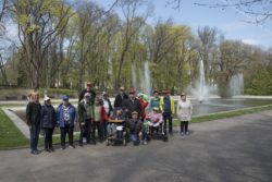 Grupa osób stojąca przed fontanną w parku.