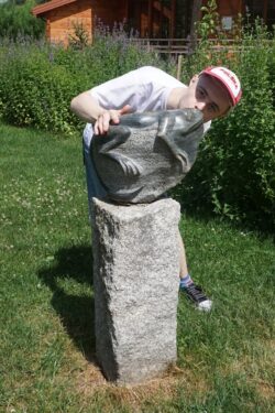 Chłopiec całujący wykonaną z kamienia rzeźbę żaby.