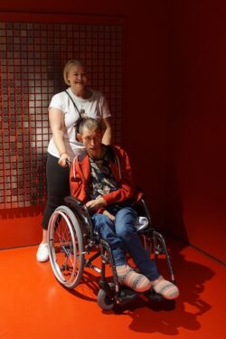 Kobieta i mężczyzna na wózku inwalidzkim wewnątrz czerwonego pomieszczenia.