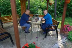 Dwaj mężczyźni grający w szachy w altanie.