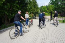 Grupa mężczyzn na rowerach przed bramą.