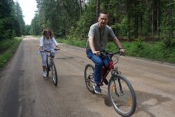 Kobieta i mężczyzna jadący rowerami leśną drogą.