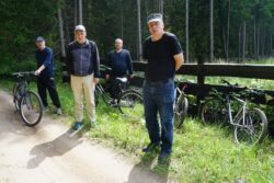 Czterech mężczyzna stojący przy rowerach w lesie.