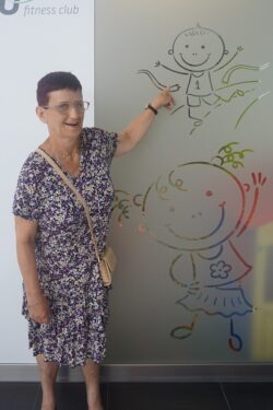 Kobieta wskazująca dłonią na rysunek na ścianie.