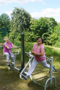 Dwie kobiety ćwiczące na podwórkowej siłowni.