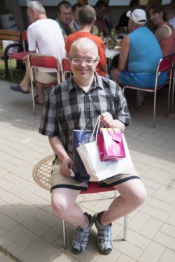 Siedzący na krześle mężczyzna trzymający otrzymane prezenty.