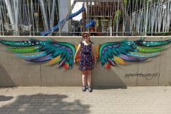 Kobieta przed muralem przedstawiającym skrzydła.