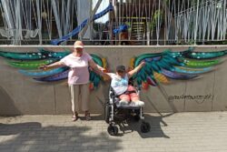 Dwie kobiety przed muralem przedstawiającym skrzydła.