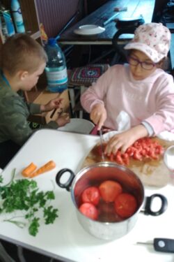 Dwoje dzieci krojące warzywa.