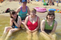 Cztery kobiety siedzące w płytkiej wodzie.