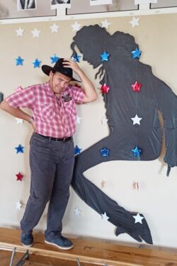 Mężczyzna w kapeluszu stojący przy ścianie na której jest umieszczony zarys postaci Michela Jacksona.