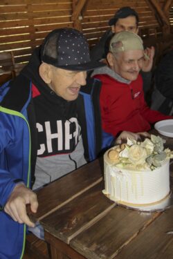 Trzech mężczyzn siedzących przy stole na którym stoi tort.