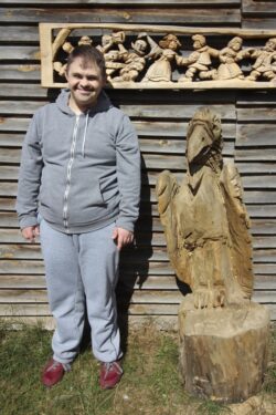 Mężczyzna stojący obok rzeźby z drewna.