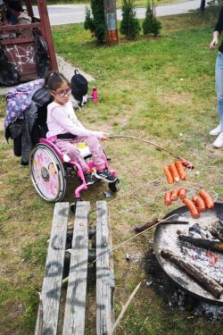 Dziewczynka na wózku inwalidzkim smarząca kiełbasę.